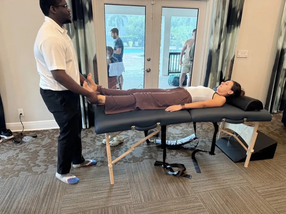 A participant on the stretching table with the practitioner at her feet
