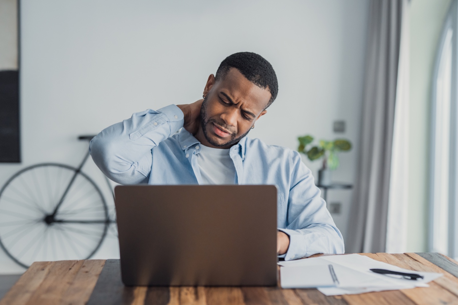 A professional stretching his neck at a desk